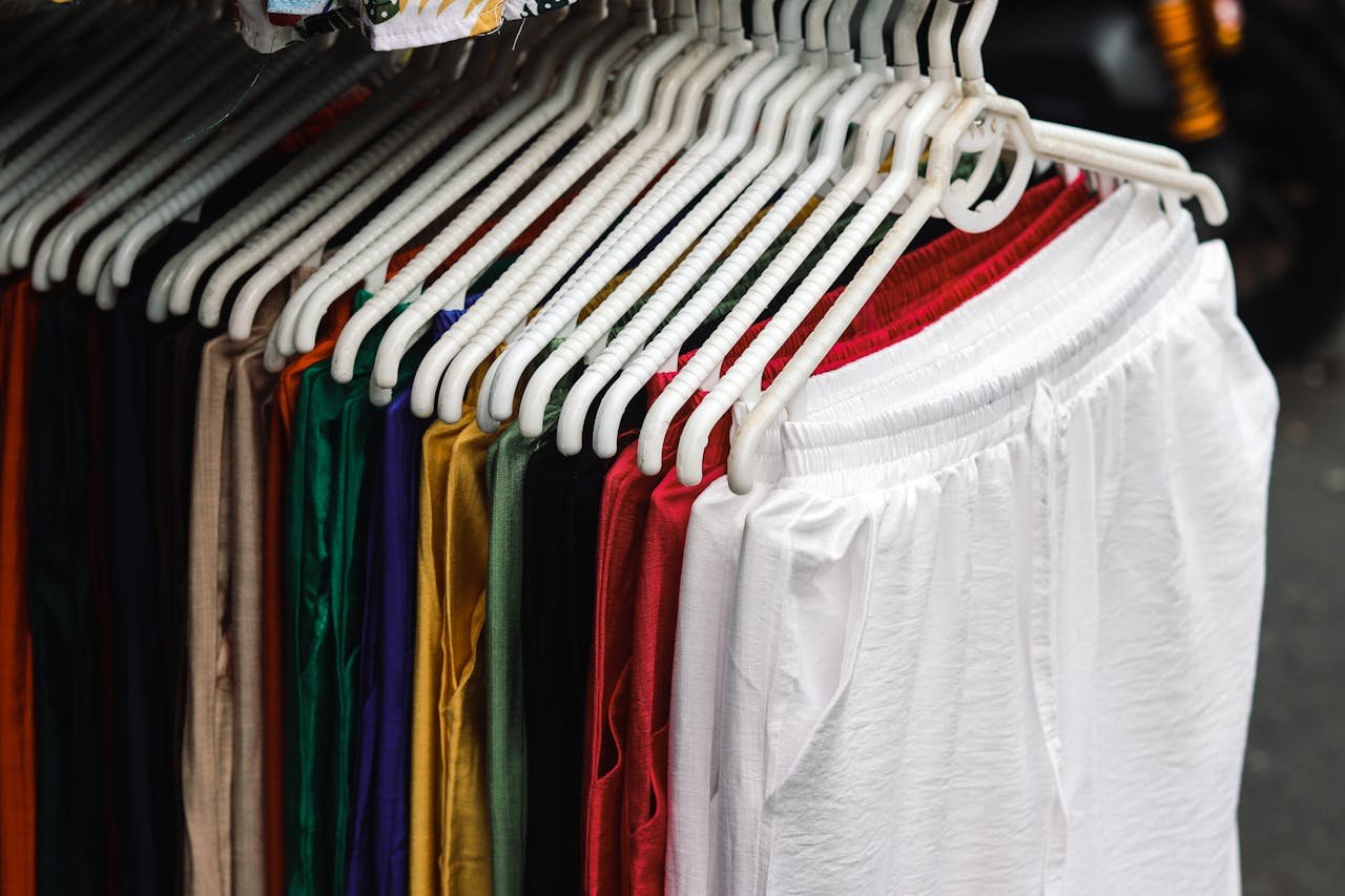 A vibrant display of pants in various colors hanging neatly on white hangers.