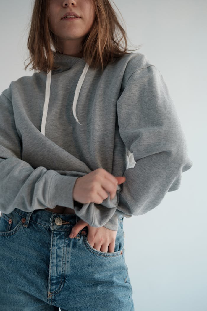 Woman in gray hoodie and jeans showing casual style indoors.